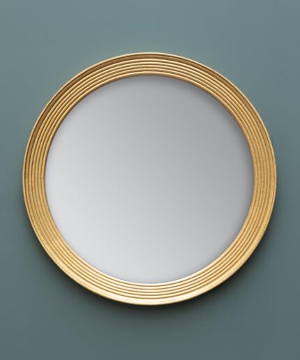 Gran espejo redondo con contorno forrado en oro.